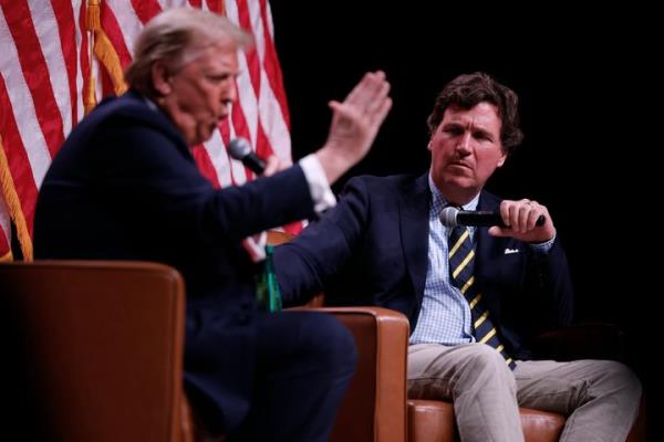 Former President Do<em></em>nald Trump, the 2024 Republican presidential nominee, sits to the left of co<em></em>nservative pundit Tucker Carlson at an event on Friday, Oct. 31, 2024, in Phoenix, Arizona.