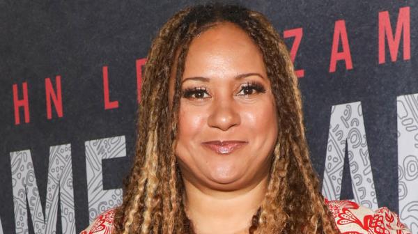 tracie thoms in braids and red print dress smirking at camera