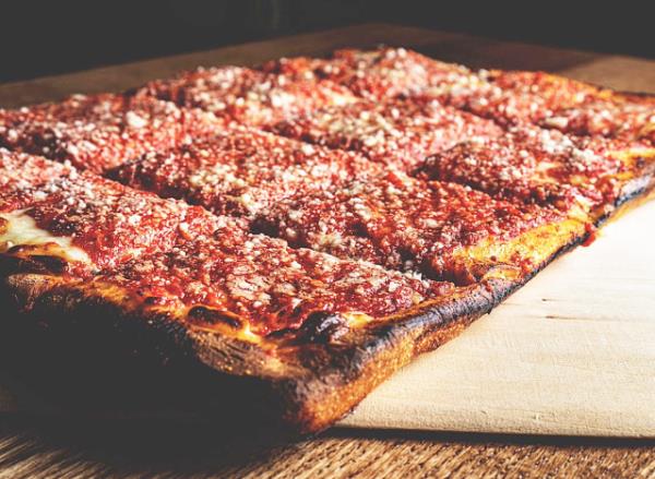 a sicilian pie on a cuting board.